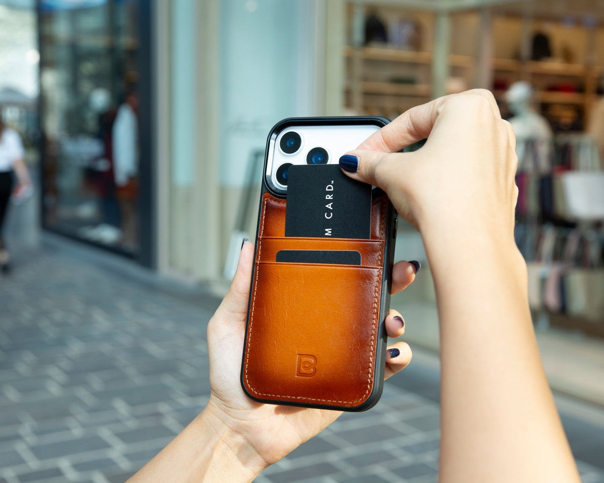 Woman placing a card into a tan leather phone case with two rear card slots