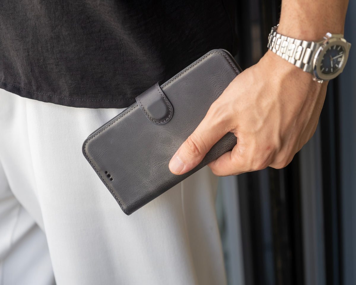 Man holding a grey leather wallet phone case with magnetic closure