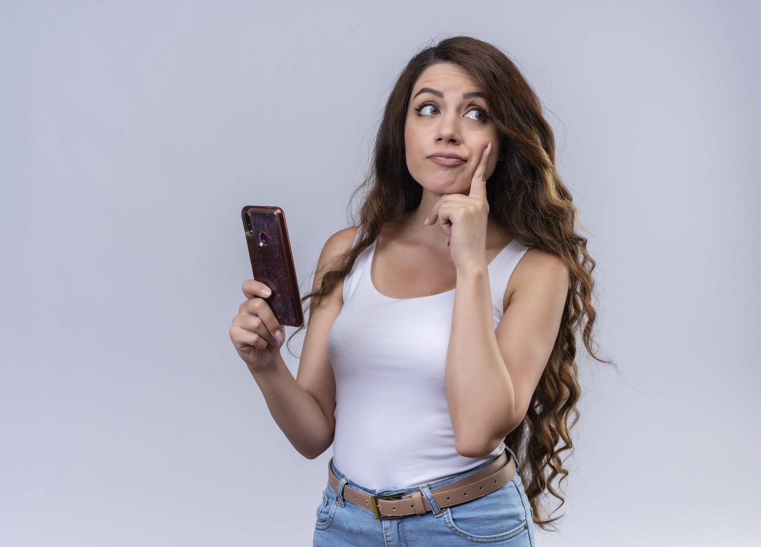 thoughtful-young-beautiful-girl-holding-mobile-phone-looking-right-side-with-finger-cheek-isolated-white-wall-with-copy-space-min