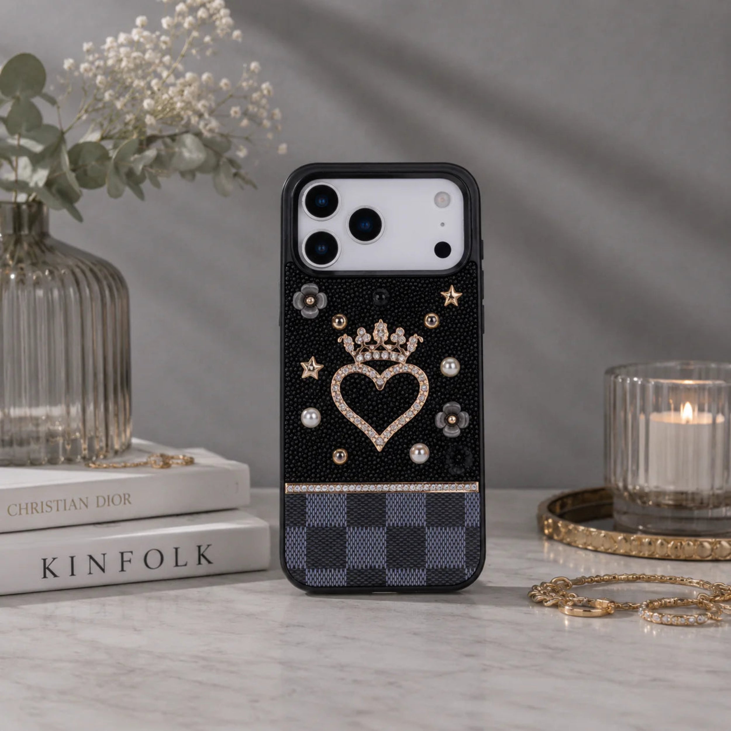 Phone case with decorative elements on a table with books and a candle