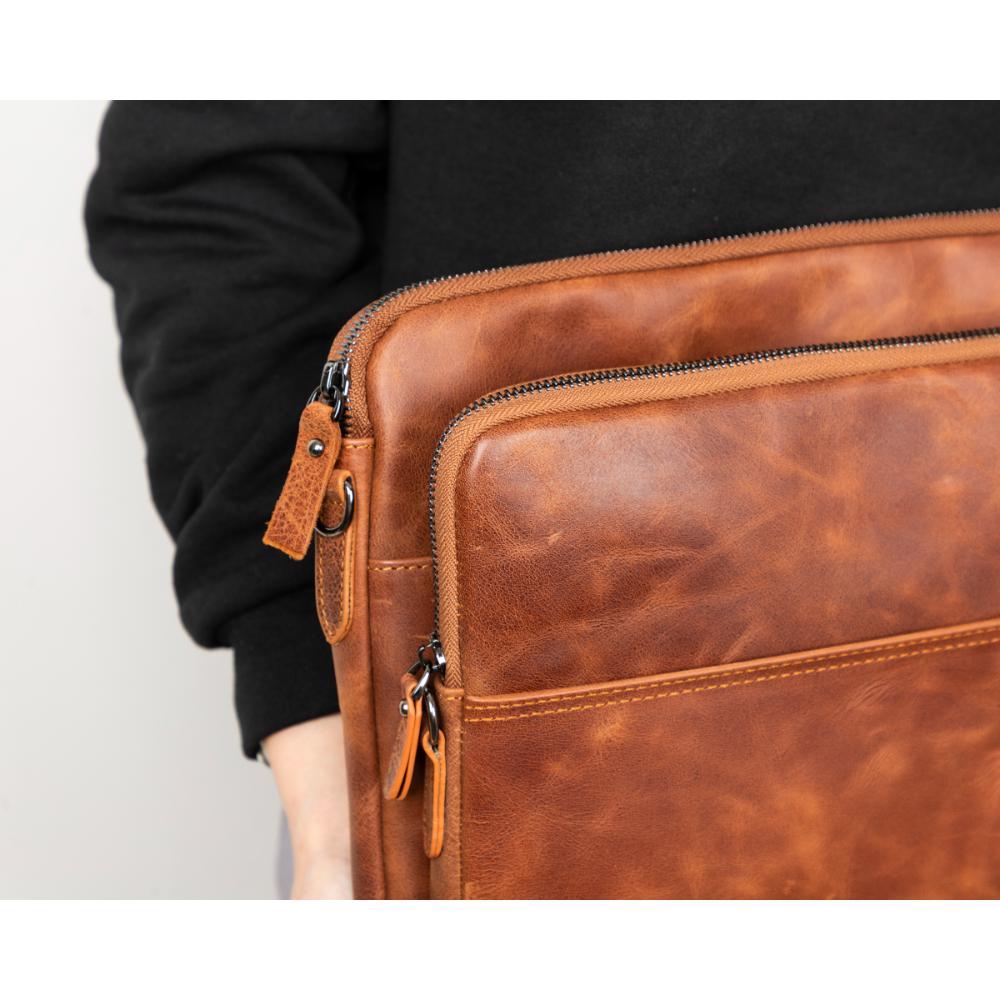 Brown leather bag held by a person against a white background