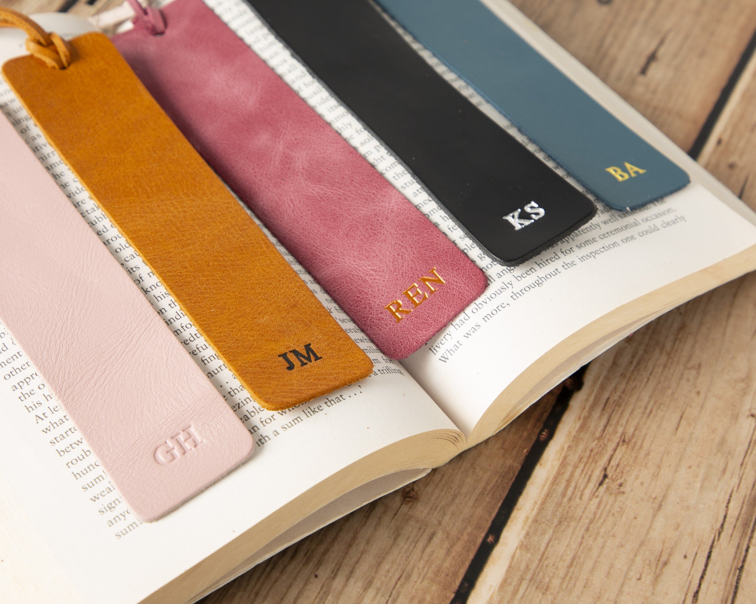 Set of colorful leather bookmarks with initials on an open book.