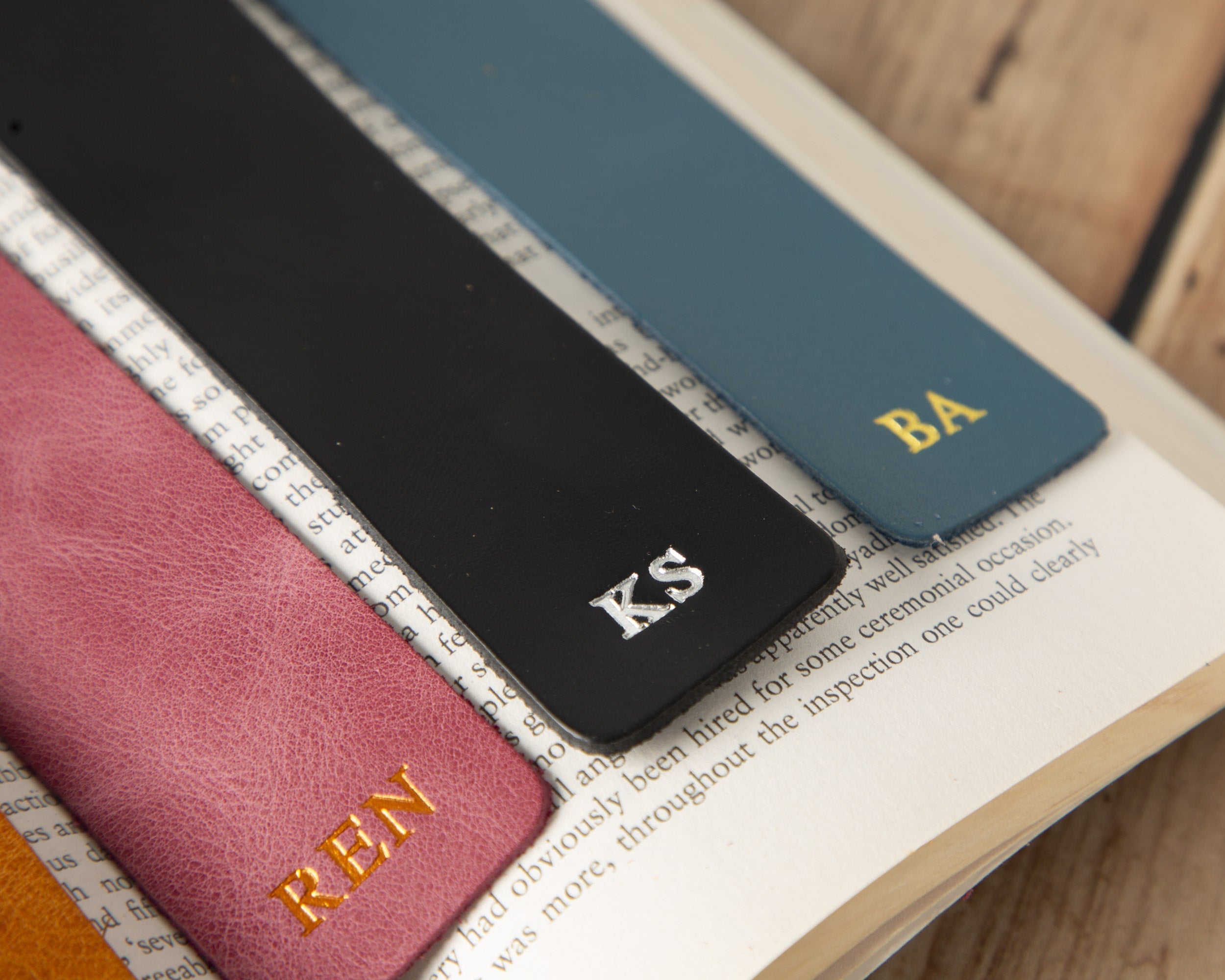 Four leather bookmarks with initials on a book