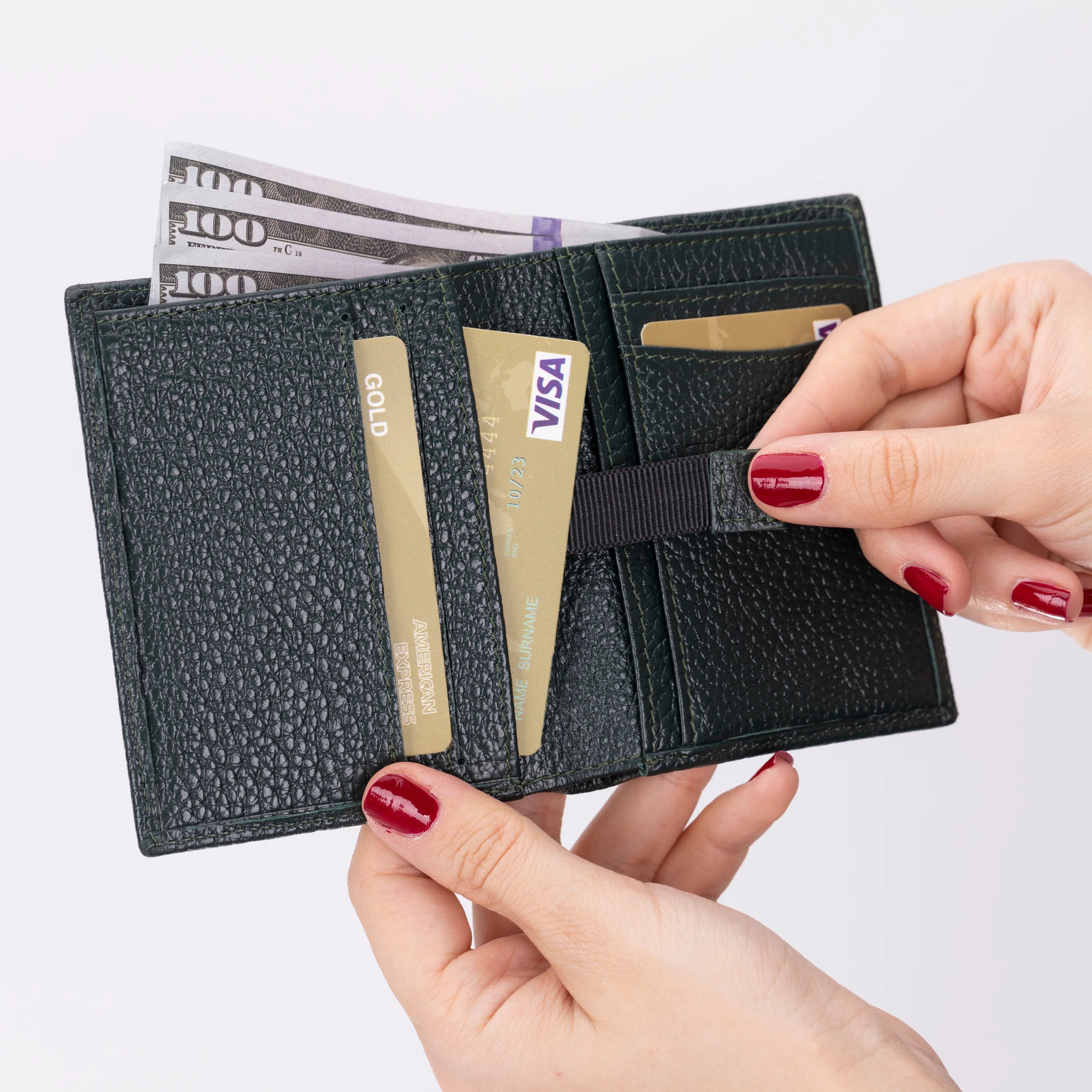 Black wallet with cards and money held by a person with red nail polish on a white background