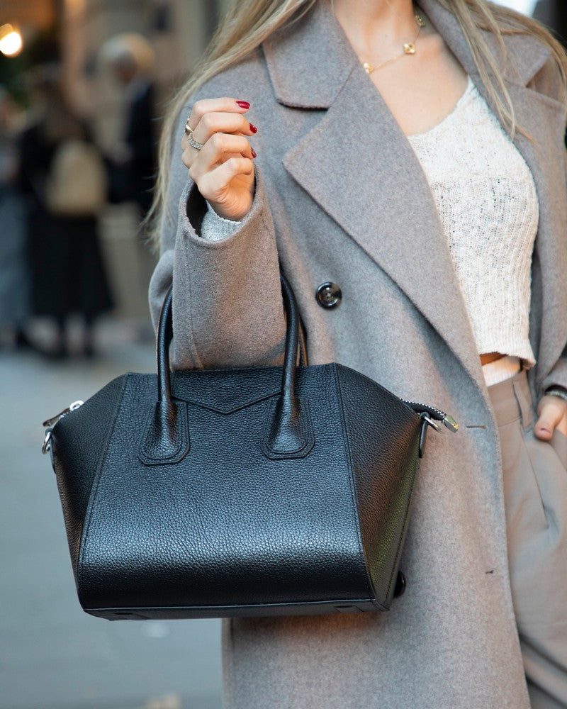 Person holding a black handbag with a blurred background