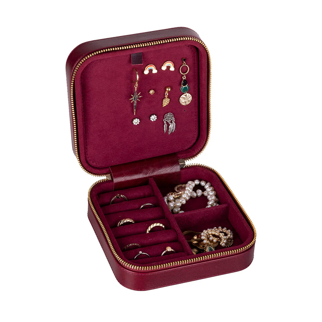 Open red jewelry box with various earrings and rings on a white background