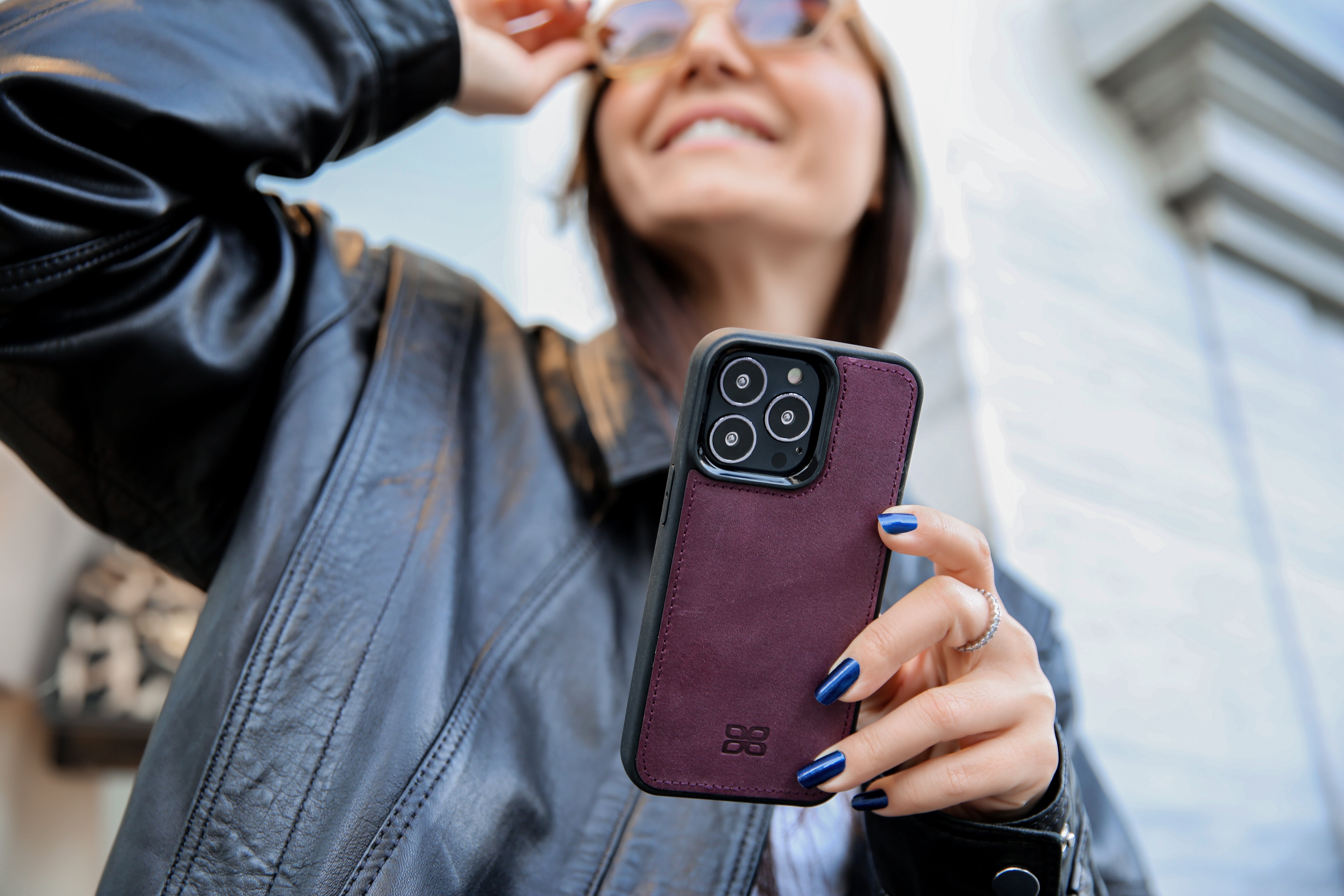 Woman holding a burgundy leather iPhone case outdoors