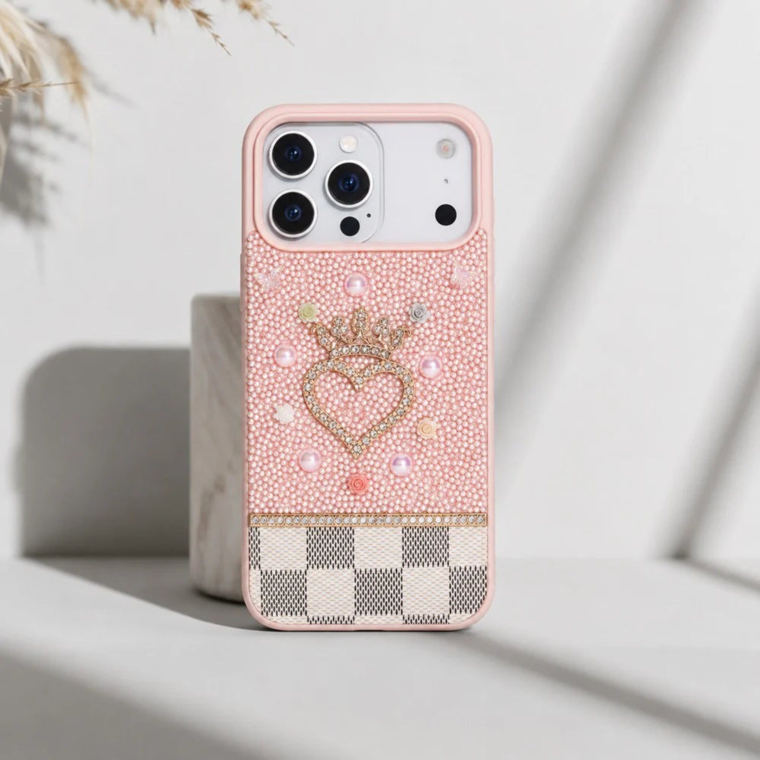 Pink phone case with decorative heart and crown design on a light background