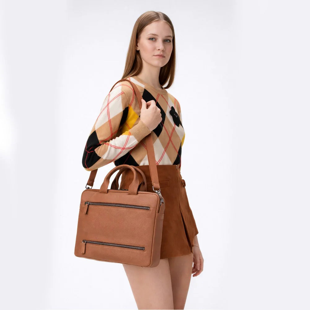 Woman holding a brown leather handbag against a white background