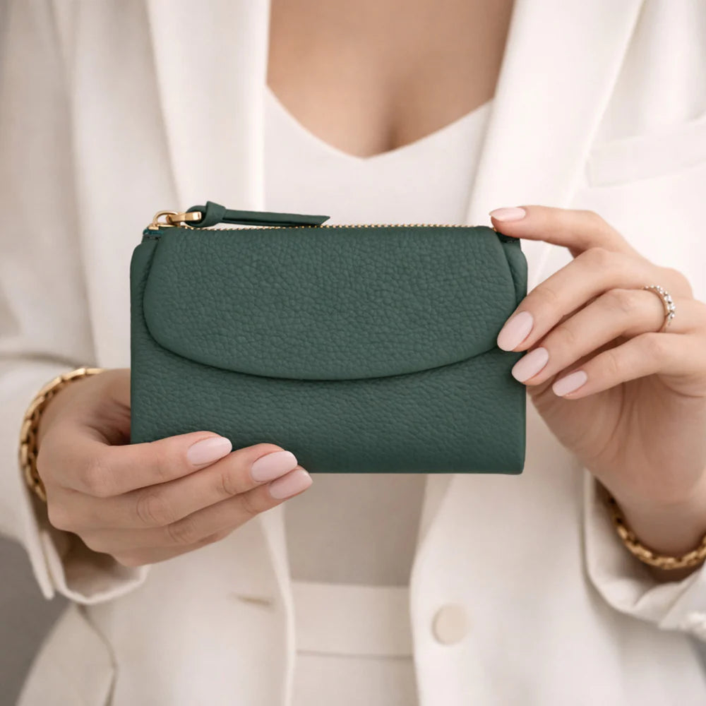 Green handbag held by a person wearing a white outfit