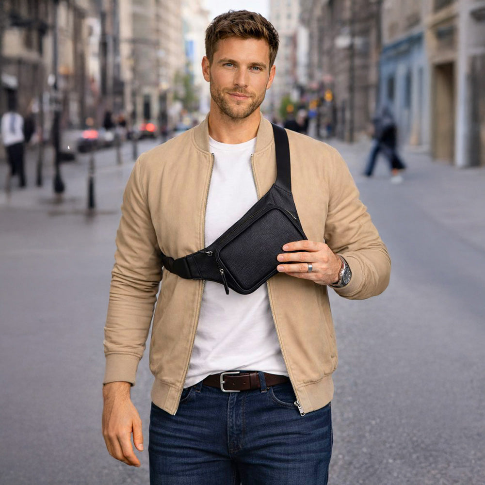 Man walking on a city street wearing a beige jacket and carrying a black waist bag.