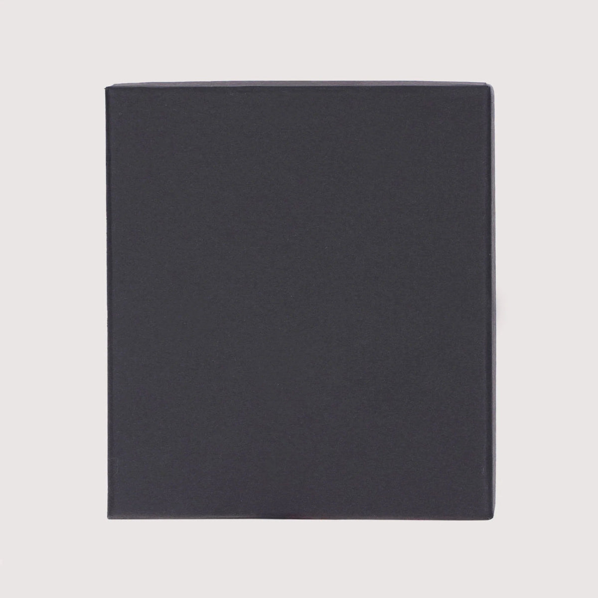 A plain, dark charcoal gray square box or cover centered on a light gray background.