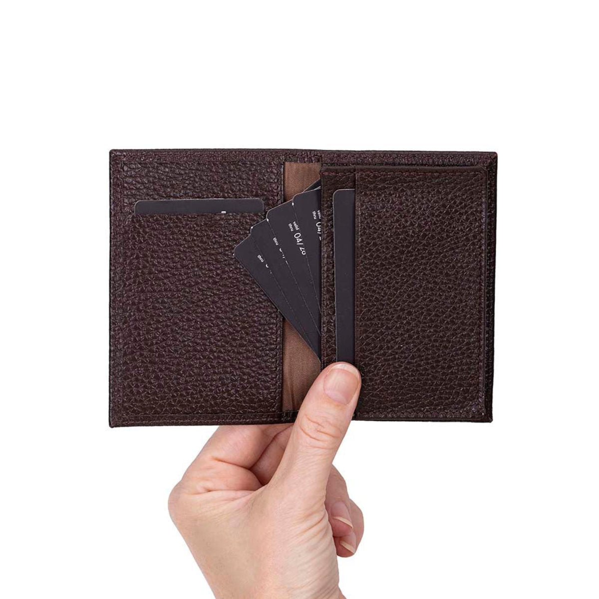 A hand holding a dark brown textured leather bifold wallet with card slots and a few black cards inserted, against a plain white background.
