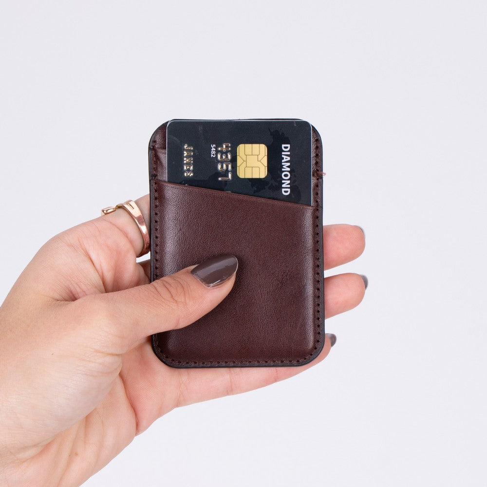 Hand holding a brown cardholder with a credit card on a light gray background