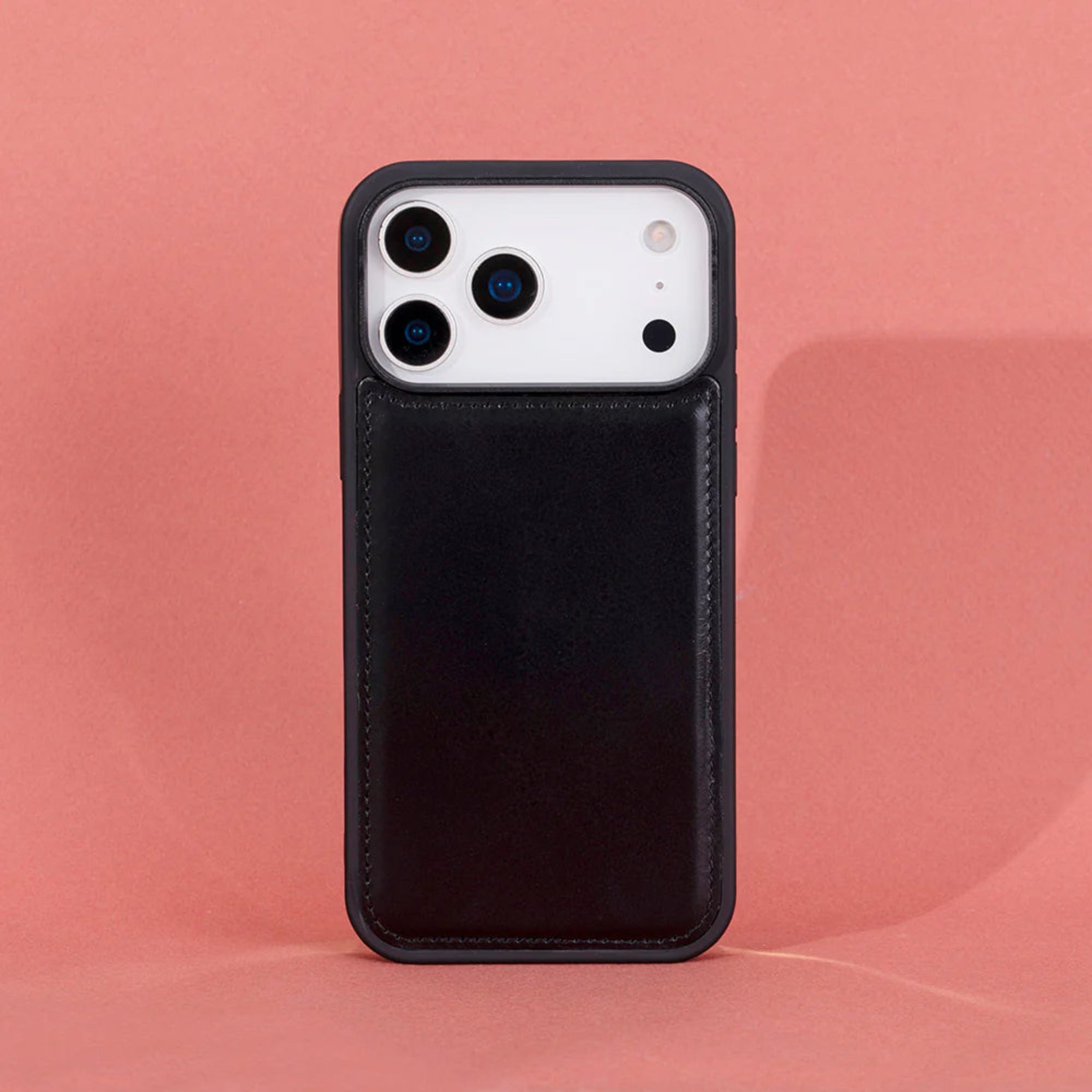 A iphone 17 pro max black leather phone case with a built-in card slot pocket, shown on a white smartphone against a solid pink background.
