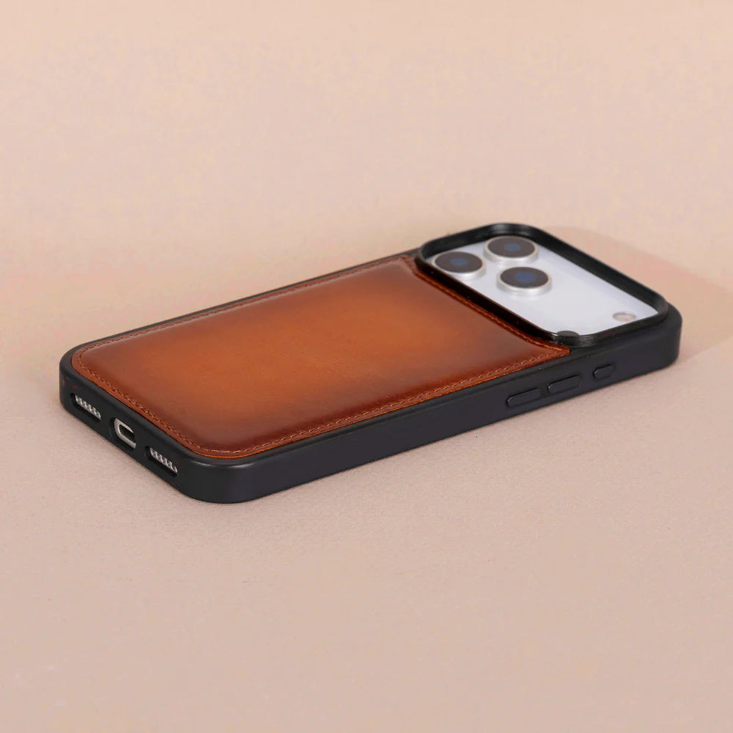 A brown leather magnetic phone case with a black bumper frame, shown on a light beige background.