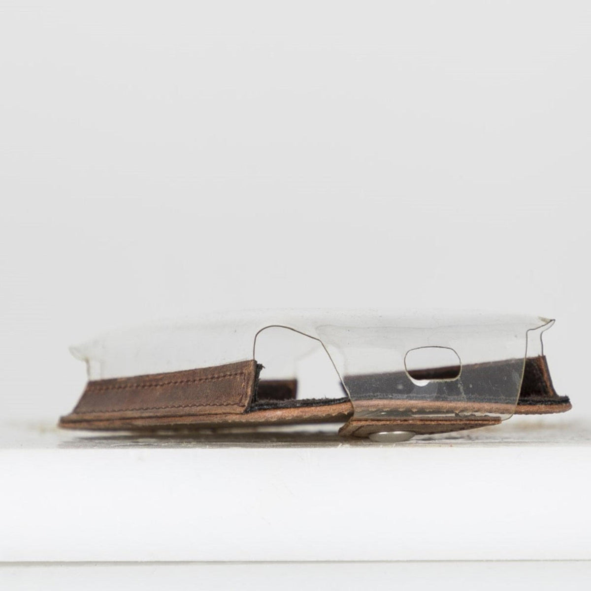 Clear plastic cover over a brown leather wallet on a white surface