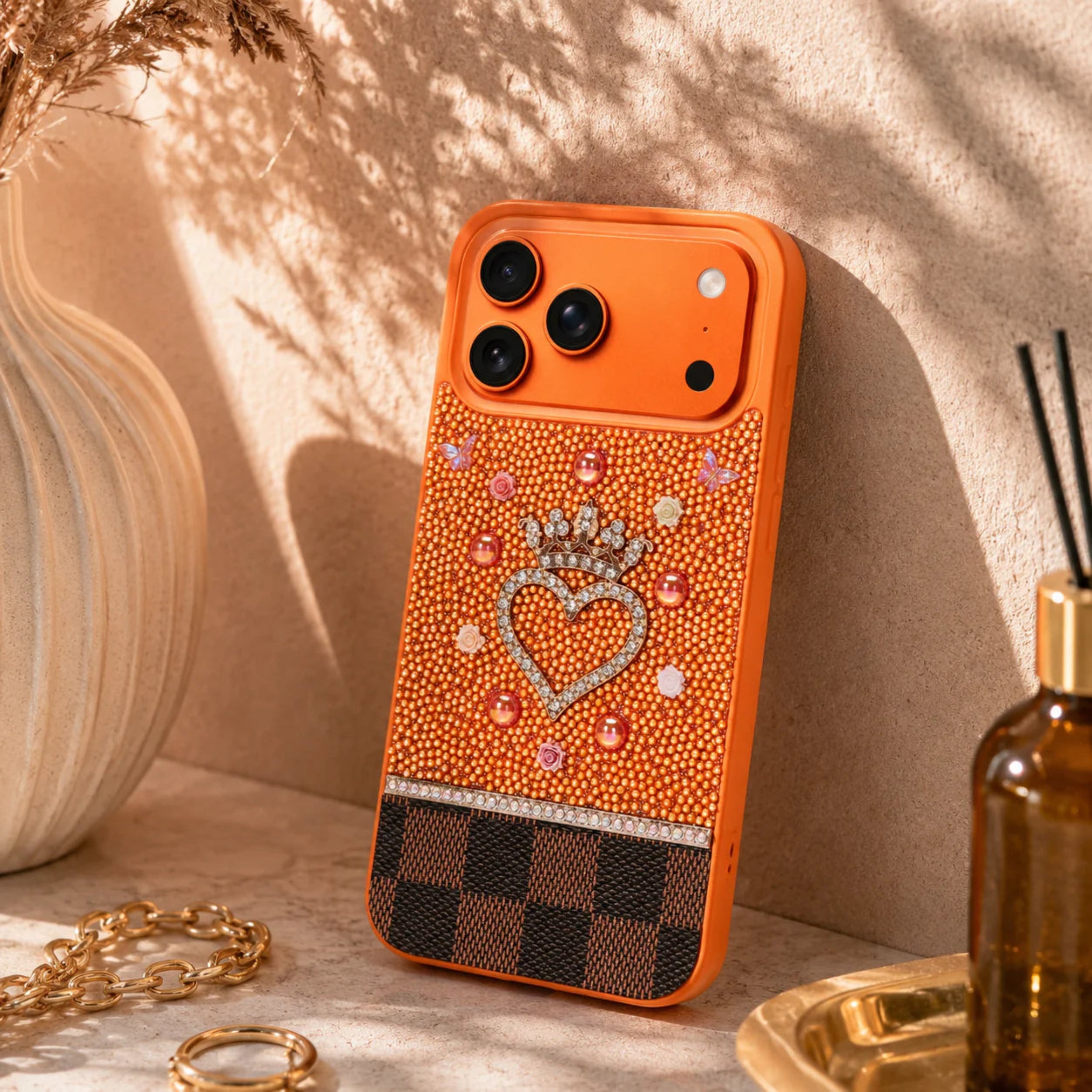 Orange phone case with decorative heart and crown design on a neutral background