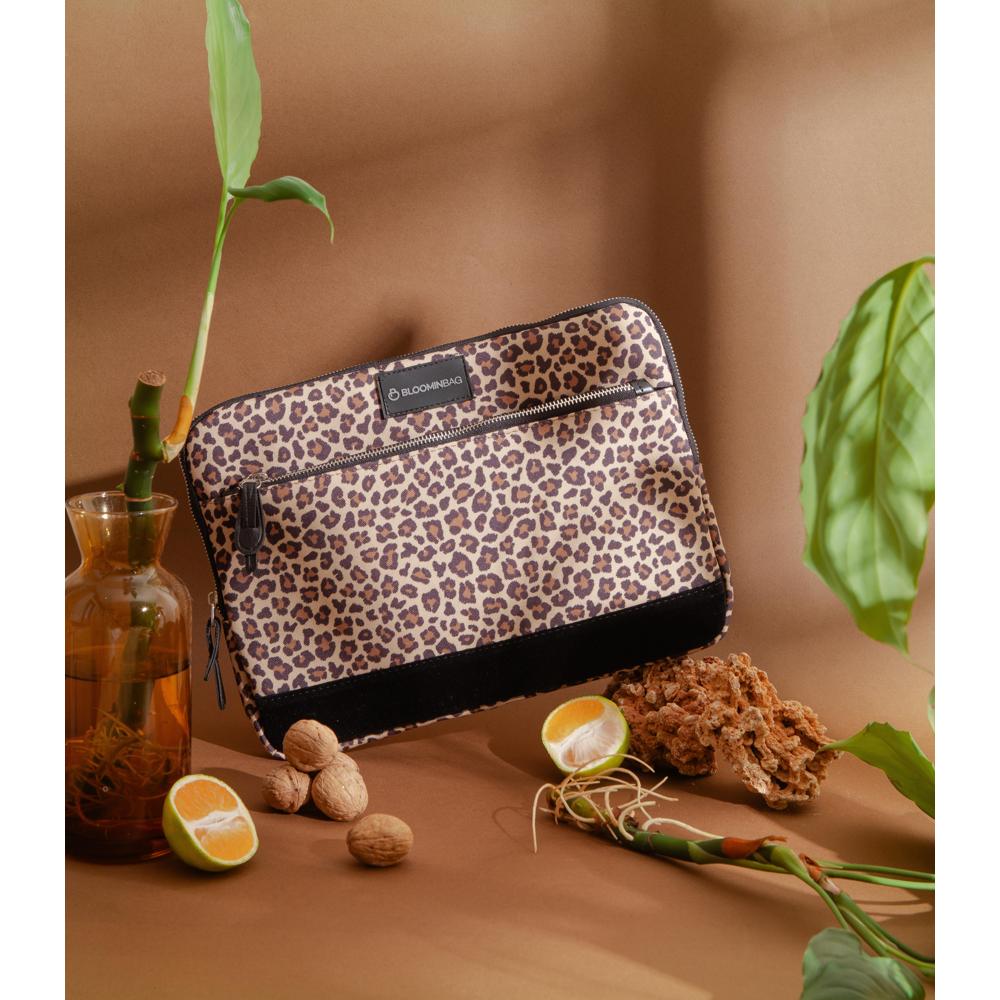 Leopard print pouch with brand logo on a brown surface with plants and natural items.